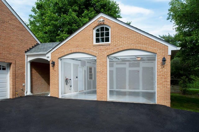 brick garage home addition with blut skies and a well-manicured lawn