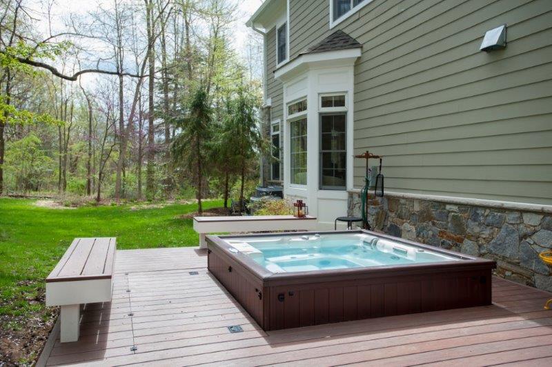 brown deck benches next to a hot tub and flagstone facade on the side of a montgomery county home