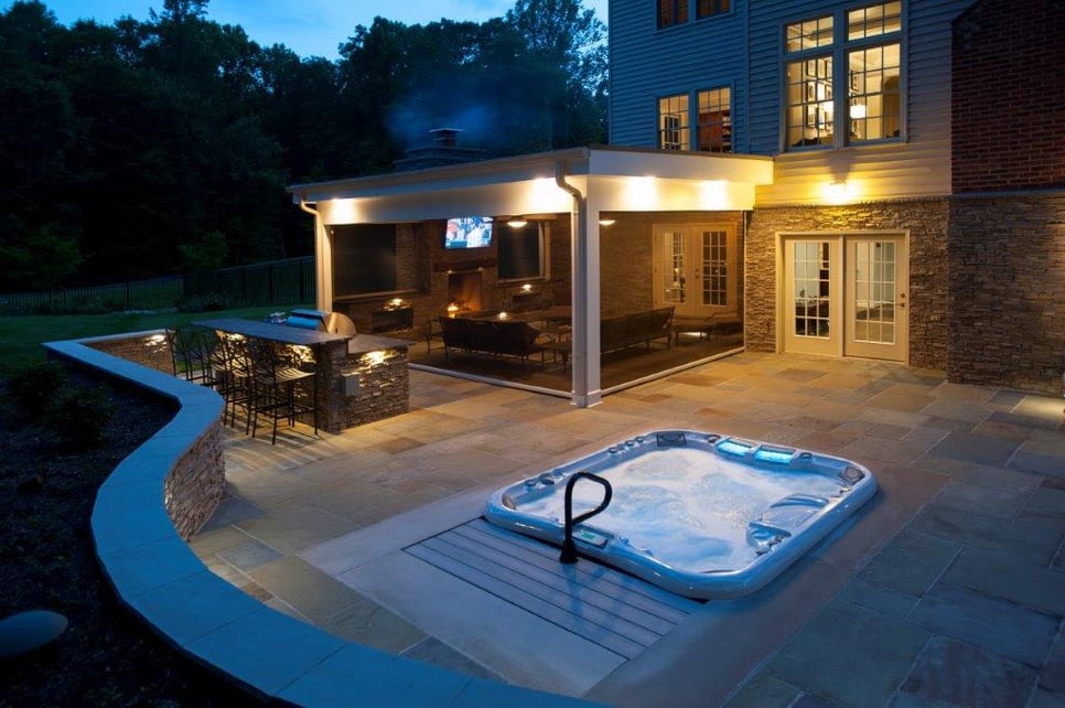 curved flagstone patio, recessed hot tub, and Phantom retractable screened potio at night Clifton, VA (1).jpg