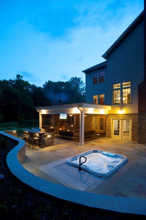 outdoor kitchen in Virginia at night with recessed hot tub