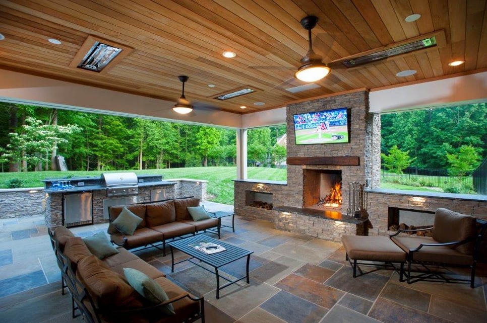 covered flagstone patio with backyard fireplace and mounted outdoor television in Virginia