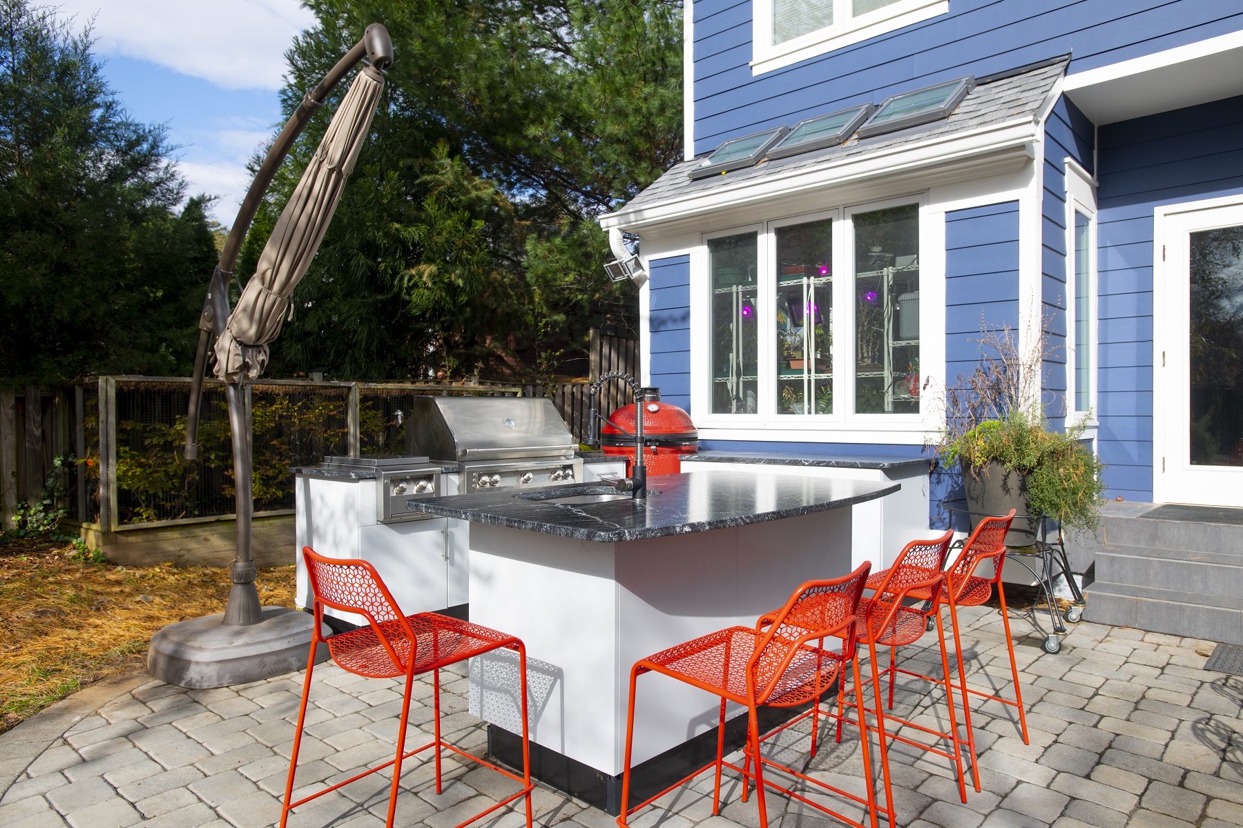 three quarter view of white powder coated stainless outdoor kitchen cabinetry with dark granite countertops in daylight